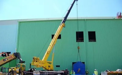 H. Brown, Inc. crane and rigging service lifting equipment into place to be slid inside of a building from the outside wall. 