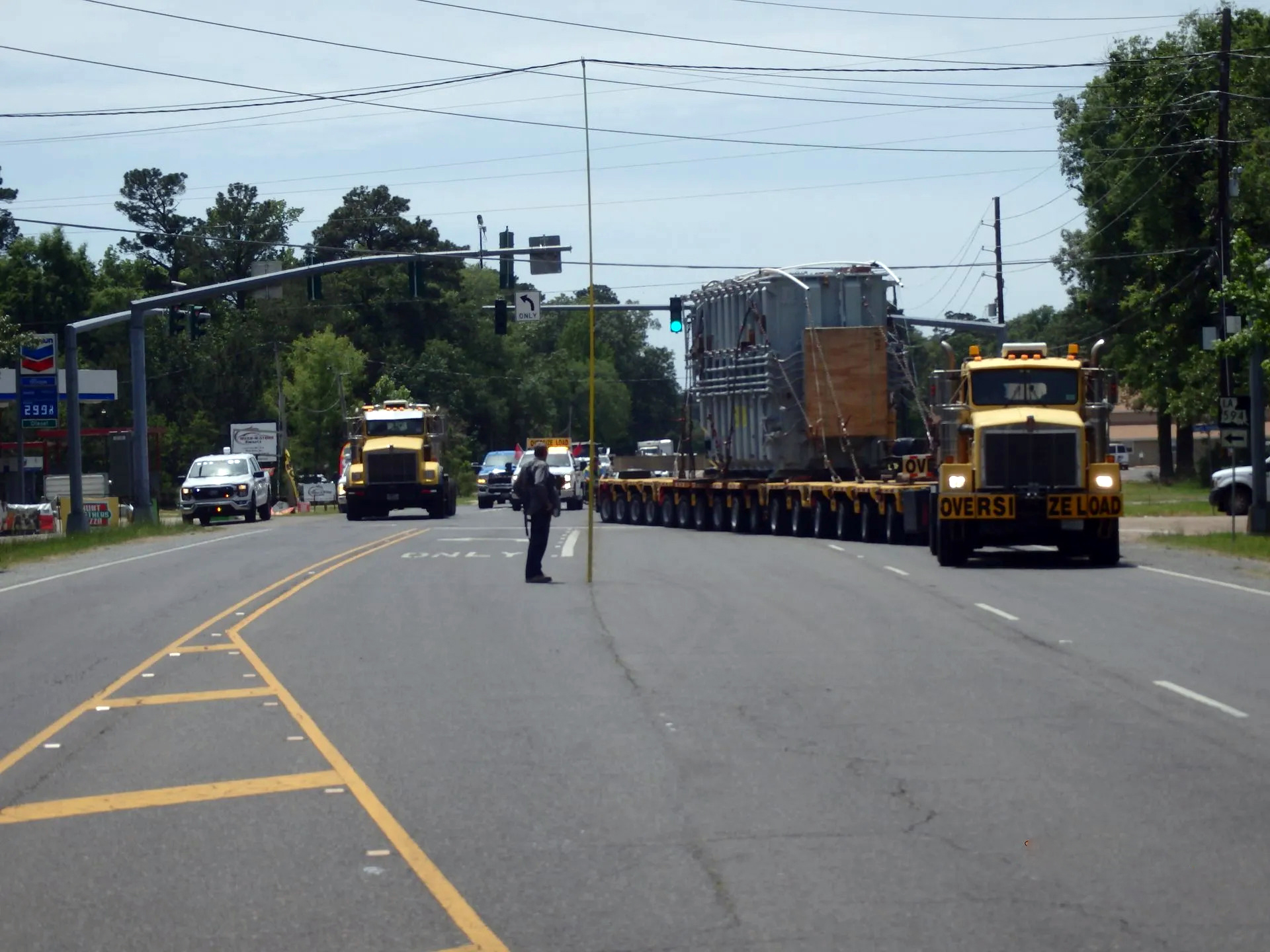 H. Brown, Inc. specialized transportation service maneuvering a loaded transformer around traffic lights with SPMTs while low hanging lines are lifted.